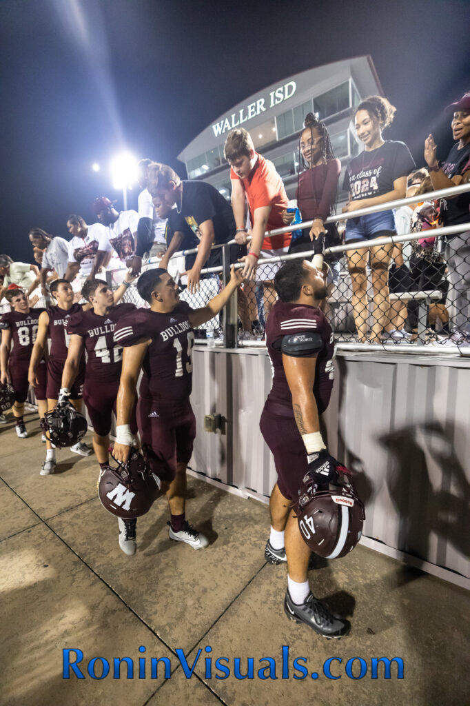 Bulldog players and cheerleaders, led by Ryan Garcia (40), thank fans for coming out after the season opener Friday night. The Waller Bulldog varsity team battles the Bryan Vikings, with the 21-6 decision favoring the Vikings. The Bulldogs next game will be against Mayde Creek in Katy ISD's Legacy Stadium. (photo courtesy RoninVisuals.com)